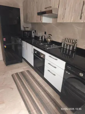 a kitchen with a black stove and a refrigerator at Appartement luxe in Oulad Akkou