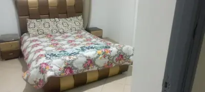 a bedroom with a bed with a floral bedspread and pillows at La perle de l'Atlas in Oulad Akkou