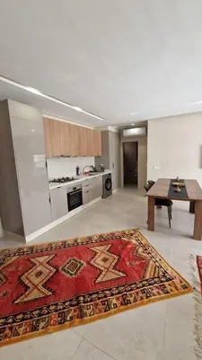 a kitchen with a table and a rug on the floor at New beachfront apartment in Oulad Akkou