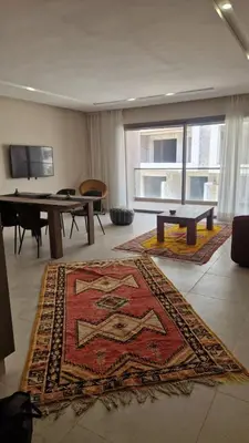 a living room with a table and a rug on the floor at New beachfront apartment in Oulad Akkou