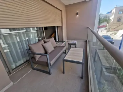 a balcony with a couch and a table at New beachfront apartment in Oulad Akkou