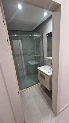 a bathroom with a glass shower and a sink at New beachfront apartment in Oulad Akkou