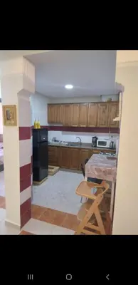a kitchen with wooden cabinets and a table and a chair at Bousstan 1er in Oulad Akkou