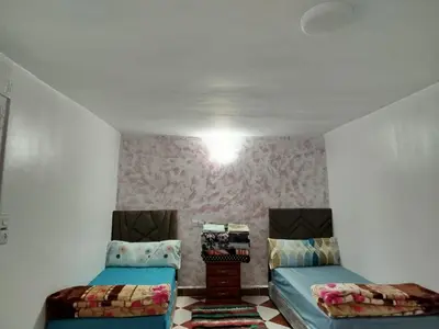 two beds in a small room with pink wallpaper at Appartement REDA in Oulad Akkou