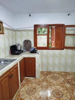 a kitchen with wooden cabinets and a tile floor at Appartement REDA in Oulad Akkou
