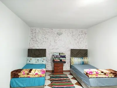 a room with two beds and a table at Appartement REDA in Oulad Akkou
