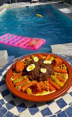 a plate of food on a table next to a pool at Ferme Maria in Tiflet