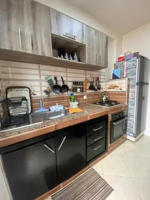 a kitchen with wooden cabinets and a stainless steel refrigerator at Family apartment between Casa and Mohammedia in Oulad Akkou