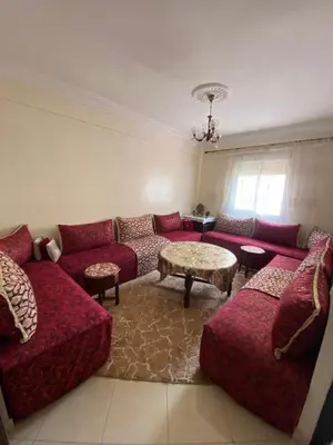 a living room with a red couch and a table at Family apartment between Casa and Mohammedia in Oulad Akkou