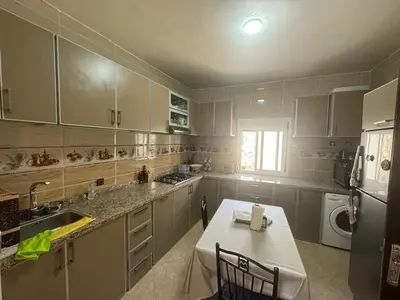 a kitchen with white cabinets and a table and a sink at Welcome to Tangier in Oulad Akkou