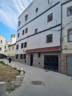 a large white building with a man walking past it at Welcome to Tangier in Oulad Akkou