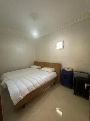 a bedroom with a bed and a blue suitcase at Welcome to Tangier in Oulad Akkou