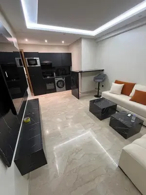 a living room with a couch and a kitchen at Appartement Moderne Hyper Centre in Oulad Akkou