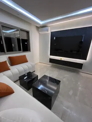 a living room with a white couch and a large tv at Appartement Moderne Hyper Centre in Oulad Akkou