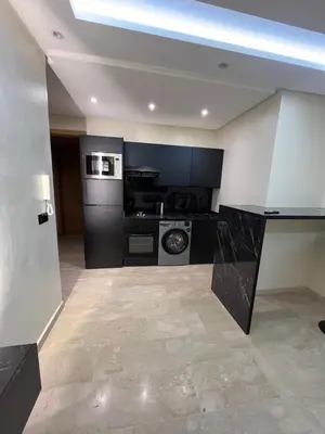 a kitchen with black and white appliances in a room at Appartement Moderne Hyper Centre in Oulad Akkou