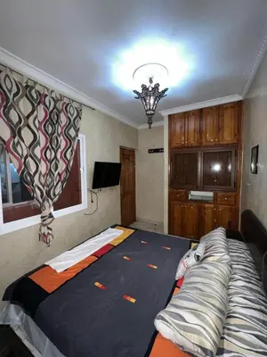 a bedroom with a large bed and a chandelier at Cozy apartment in center in Beni Mellal