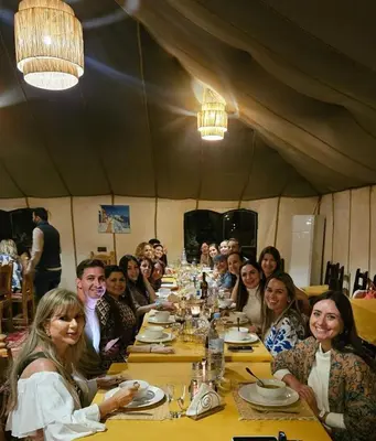 a group of people sitting at a long table at LuXURY SAHARA CAMP in Merzouga