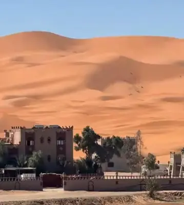 a building in front of a sand dune at LuXURY SAHARA CAMP in Merzouga