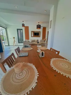 a large wooden table with chairs and a living room at Chic Duo Villas with Pool & Hammam in Ourika