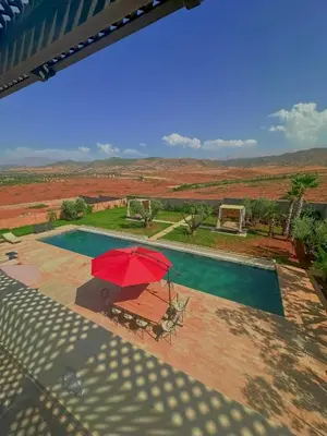 a pool with a red umbrella and a table with a bench at Chic Duo Villas with Pool & Hammam in Ourika