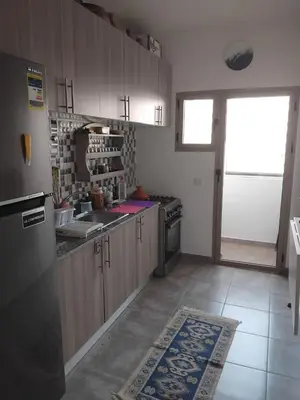 a kitchen with wooden cabinets and a refrigerator at Appartement moderne - Marrakech in Oulad Akkou