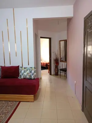 a living room with a red couch and a hallway at caprice apparemment in Ifrane
