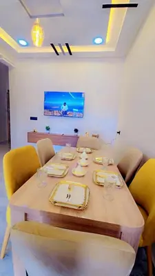 a dining room table with yellow chairs and a television at Luxuriöse Wohnung in Fez in Fès