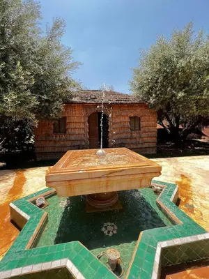 a fountain in front of a brick building with trees at Intimate villa Private pool et Atlas view in Sidi Bouzguia