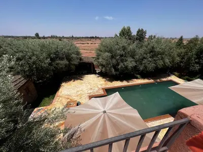 a swimming pool with umbrellas next to a field at Intimate villa Private pool et Atlas view in Sidi Bouzguia