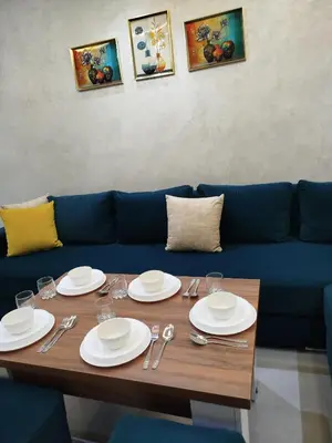 a table with plates and silverware on a blue couch at Le refuge de Vittel 3 in Ifrane