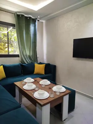 a living room with a table and a blue couch at Le refuge de Vittel 3 in Ifrane