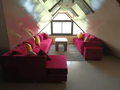 a living room with a red couch and a table at Le refuge de Vittel in Ifrane