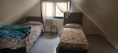 a bedroom with two beds and a window and a stair case at Le refuge de Vittel in Ifrane