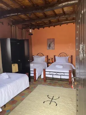 a room with two beds and a rug at Dar Imane - Magnifique ferme en pleine nature in Ouarzazate