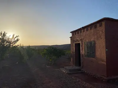 an old brick building with a door in a field at Dar Imane - Magnifique ferme en pleine nature in Ouarzazate