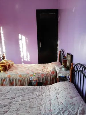 a bedroom with two beds and a purple wall at Chambre à deux lit in Fès