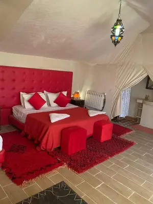 a bedroom with a red bed with a red headboard at Desert luxury tents in Merzouga