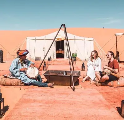 a group of people sitting in the desert at Desert luxury tents in Merzouga
