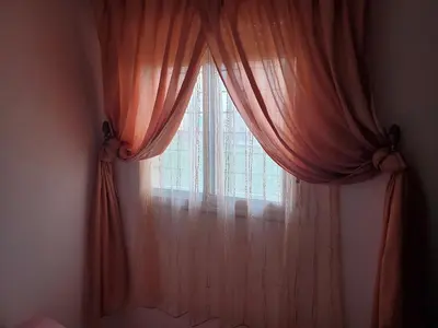 a window with orange curtains in a bedroom at le bon coin in Ifrane