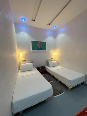 two twin beds in a room with blue lights at Tigami N-Laman in Iskhissane