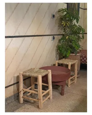 a bench and two stools in front of a wall at Tigami N-Laman in Iskhissane