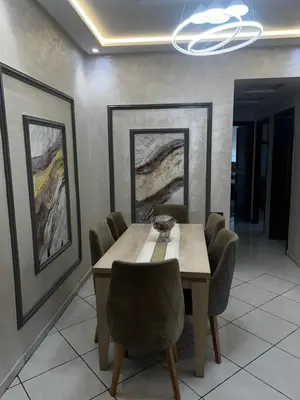 a dining room with a table and chairs and paintings at Beautiful large apartment in Fès