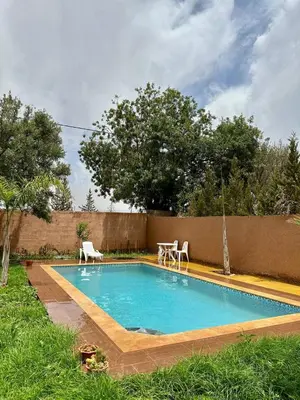 a swimming pool with two chairs and a table at Villa Zine in Aït Namous