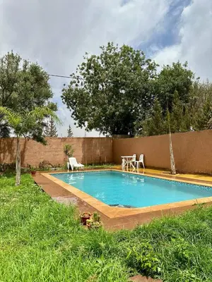 a small swimming pool in a yard with two chairs at Villa Zine in Aït Namous