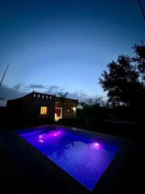 a swimming pool with purple lights in front of a house at Villa Zine in Aït Namous