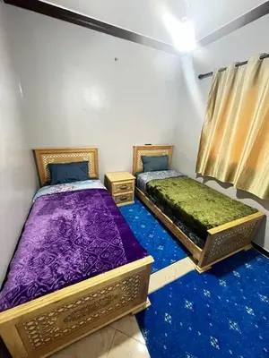 two beds in a room with blue carpet at desert appartement in Merzouga