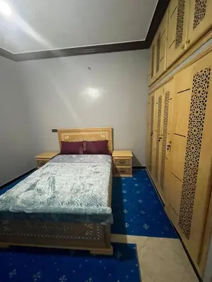a small bedroom with a bed and some wooden doors at desert appartement in Merzouga
