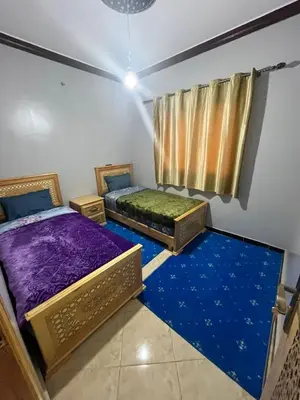 two beds in a room with blue carpet at desert appartement in Merzouga