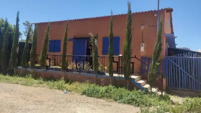 a fence in front of a house with trees at Villa de rêve in Bine el Ouidane