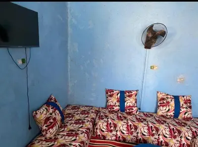 a bedroom with a bed with pillows and a fan at Housse stander merzouga in Merzouga